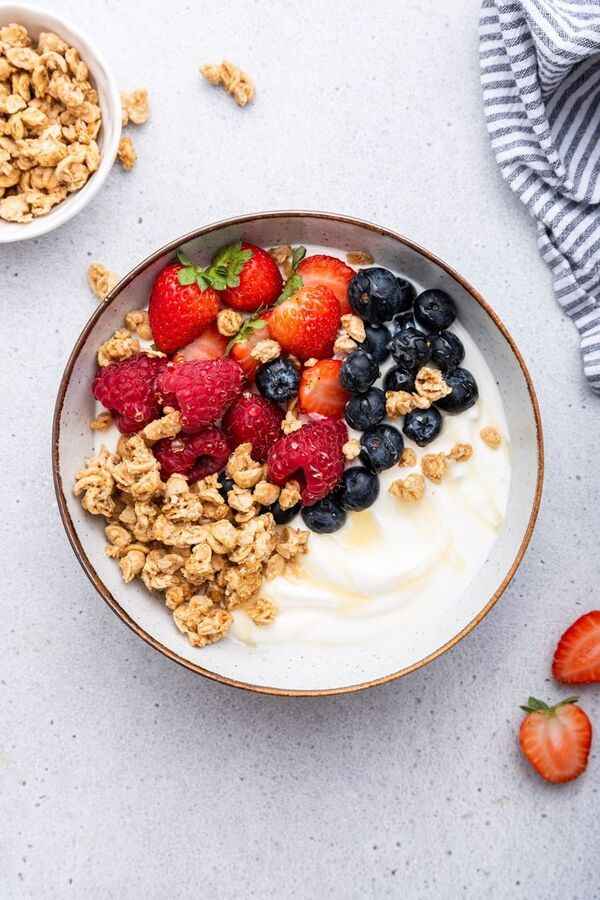 Desayuno con yogur, cereales y fruta servido en un tazón